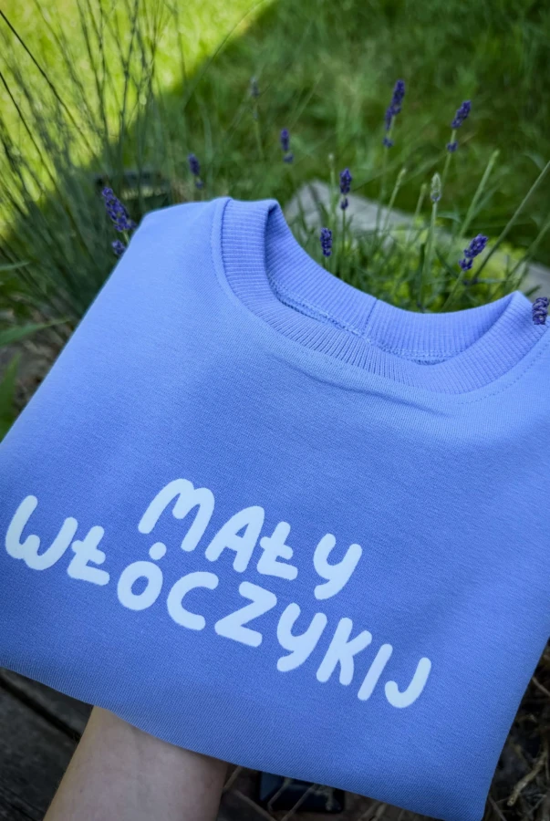 Bluza dziecięca oversize w kolorze lawendowym z napisem MAŁY WŁÓCZYKIJ dla małego podróżnika podróże wyjazdy wakacje