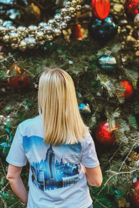 Koszulka podróżnicza z panoramą Nowego Jorku – widok z tyłu na modelce przy choince w Nowym Jorku
